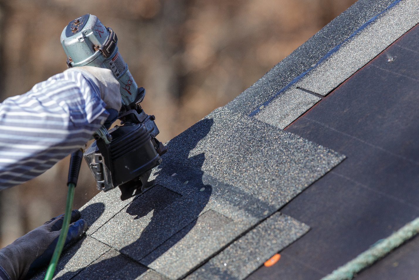 A man standing on top of a roof with a tool box.