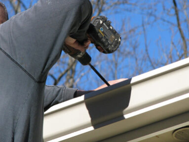 A man working on the gutter of his home.