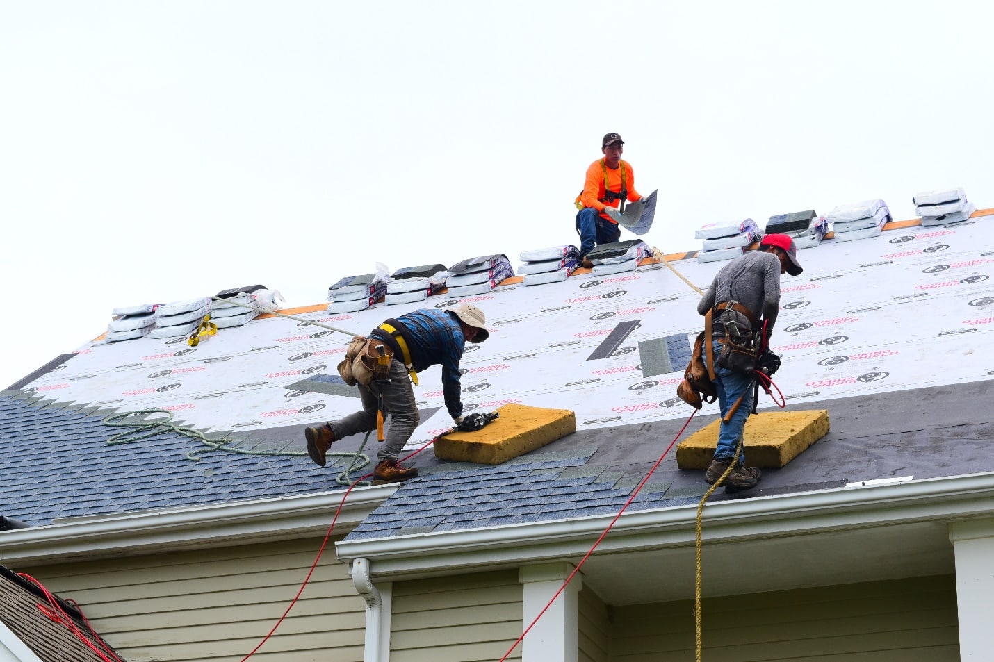 A group of men working on the roof of a house.