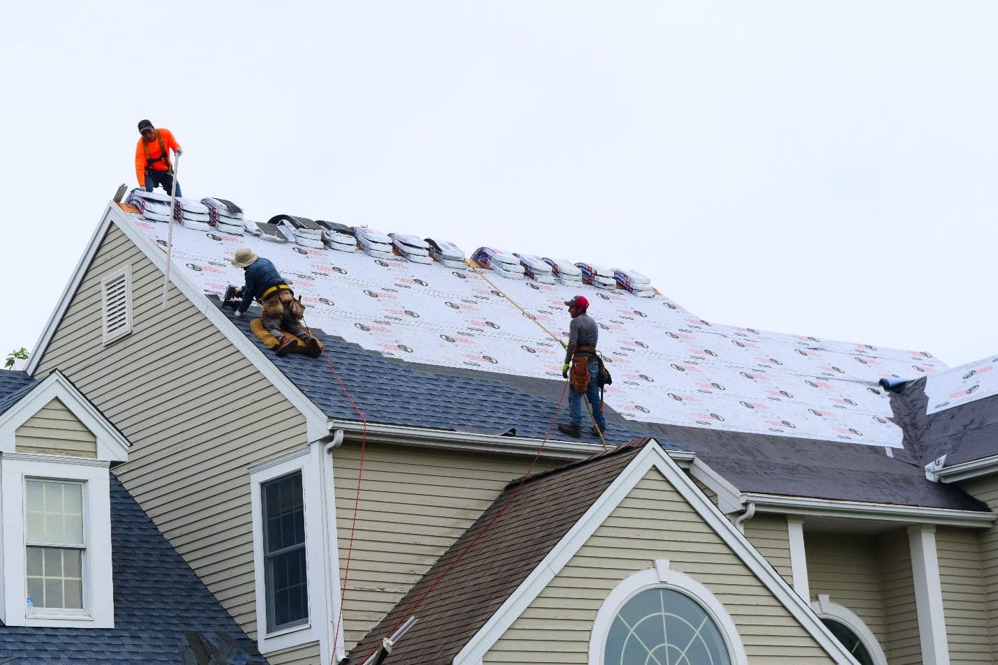 A group of men working on the roof of a house.