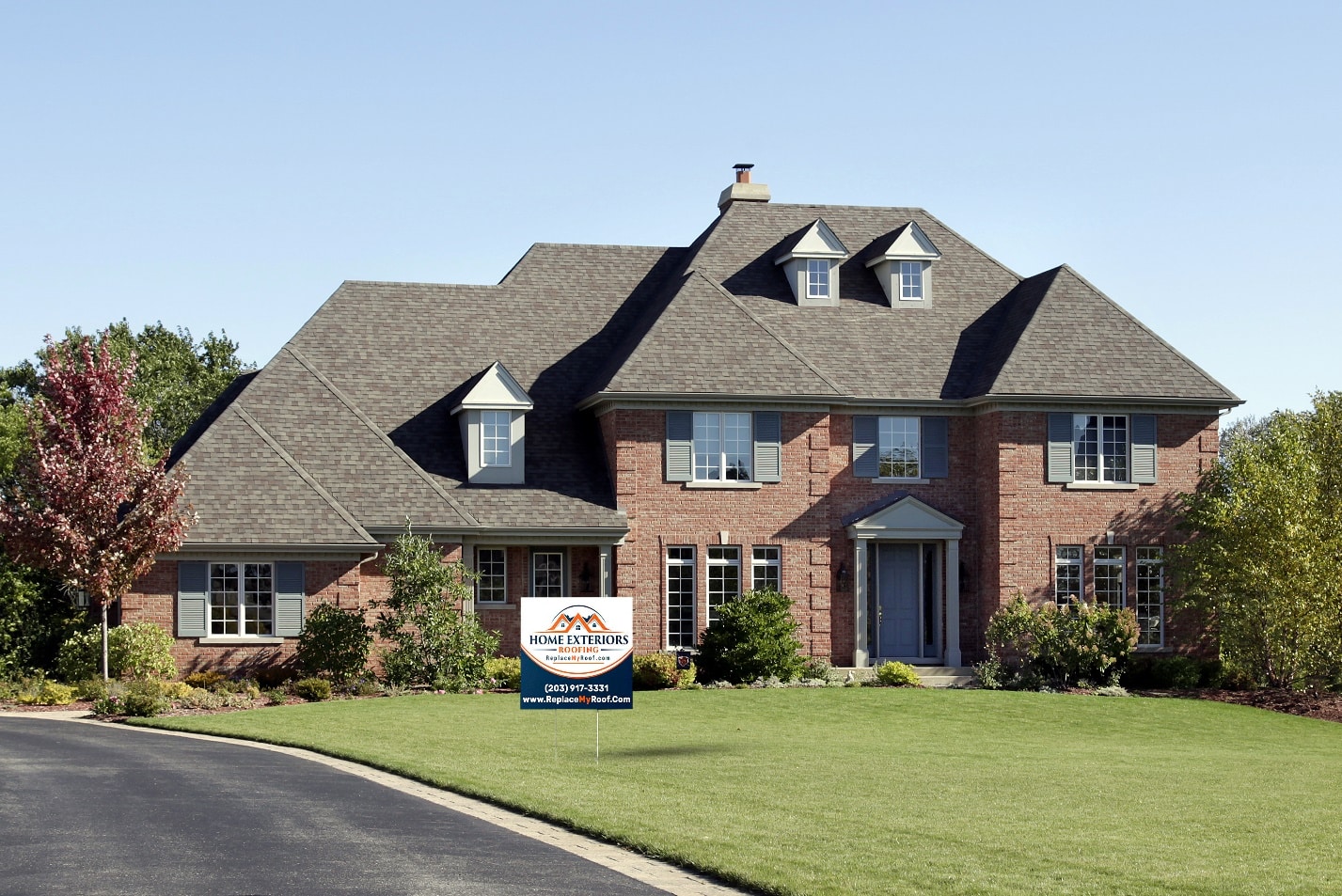 A large brick house with a sign in front of it.